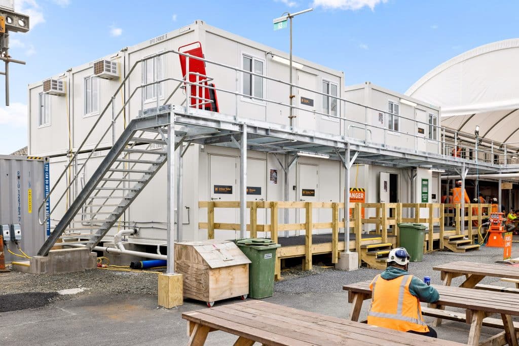 A construction worker sits outside a portable site office.