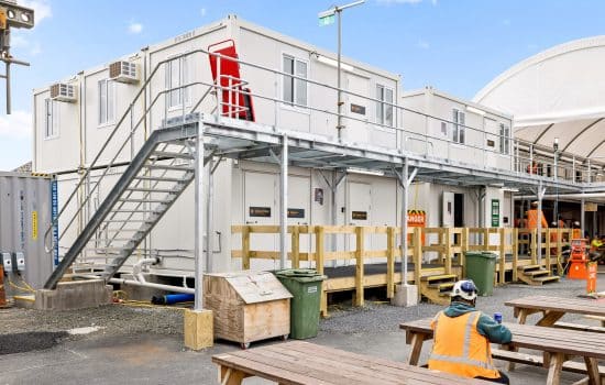 A construction worker sits outside a portable site office.