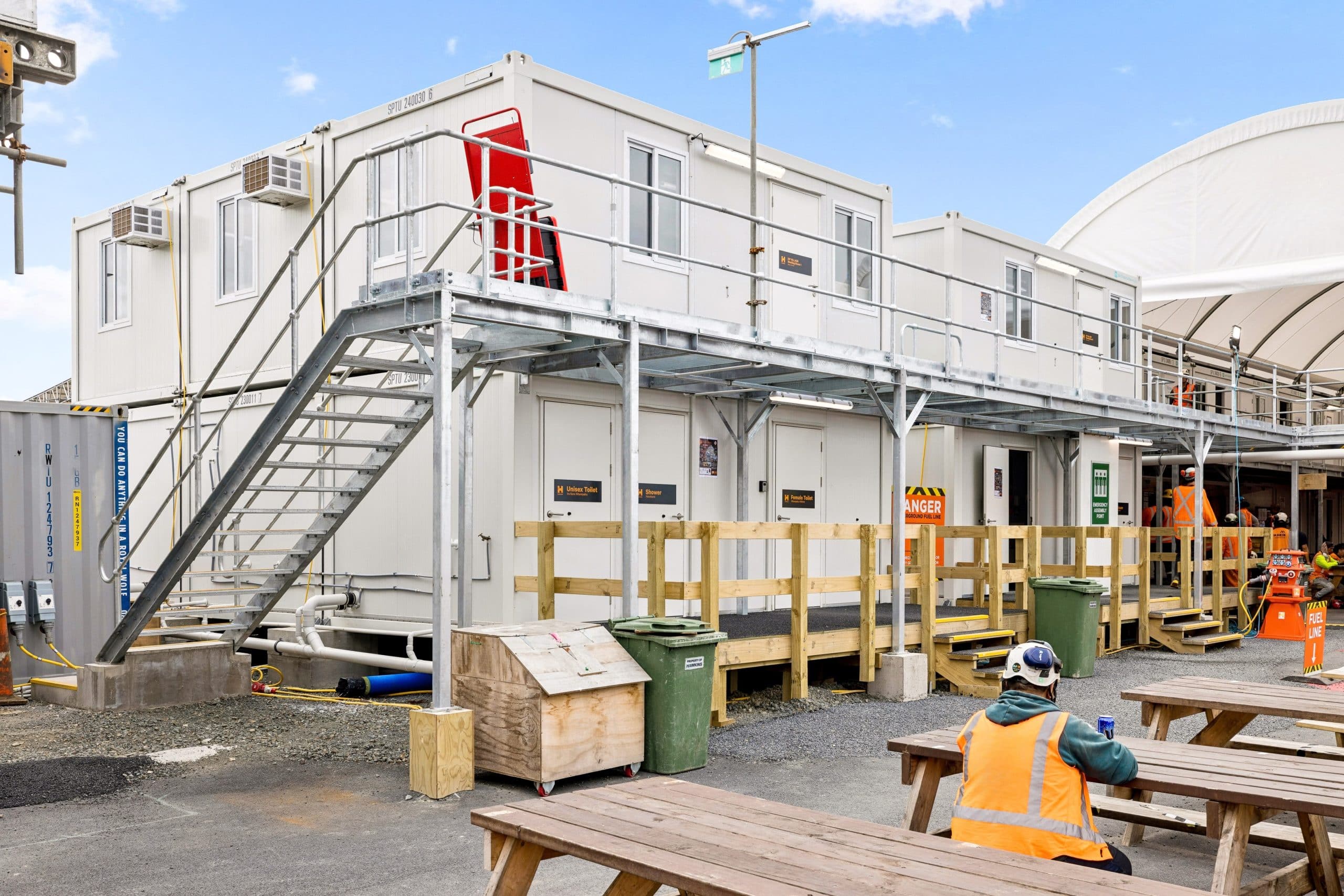 A construction worker sits outside a portable site office.