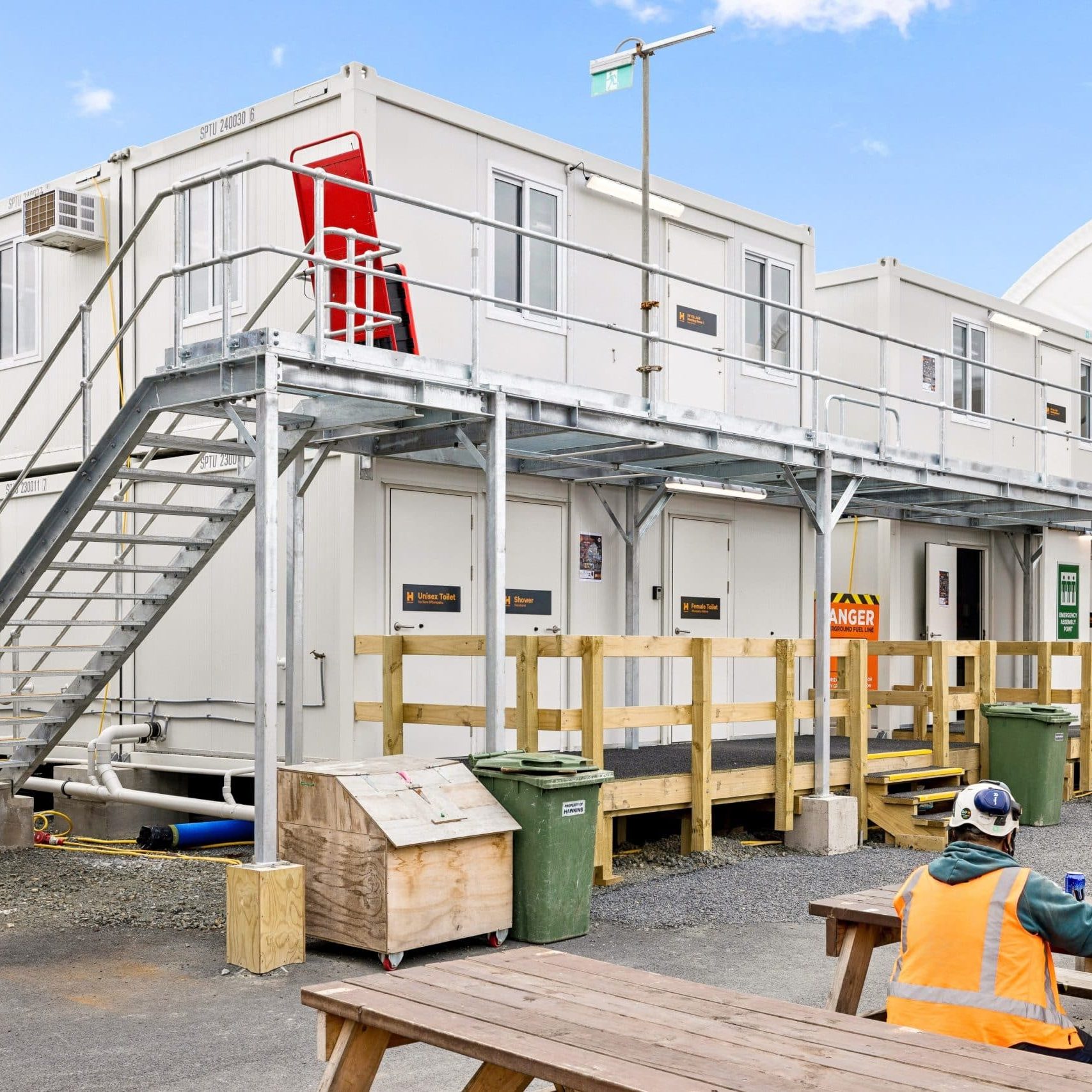 A construction worker sits outside a portable site office.